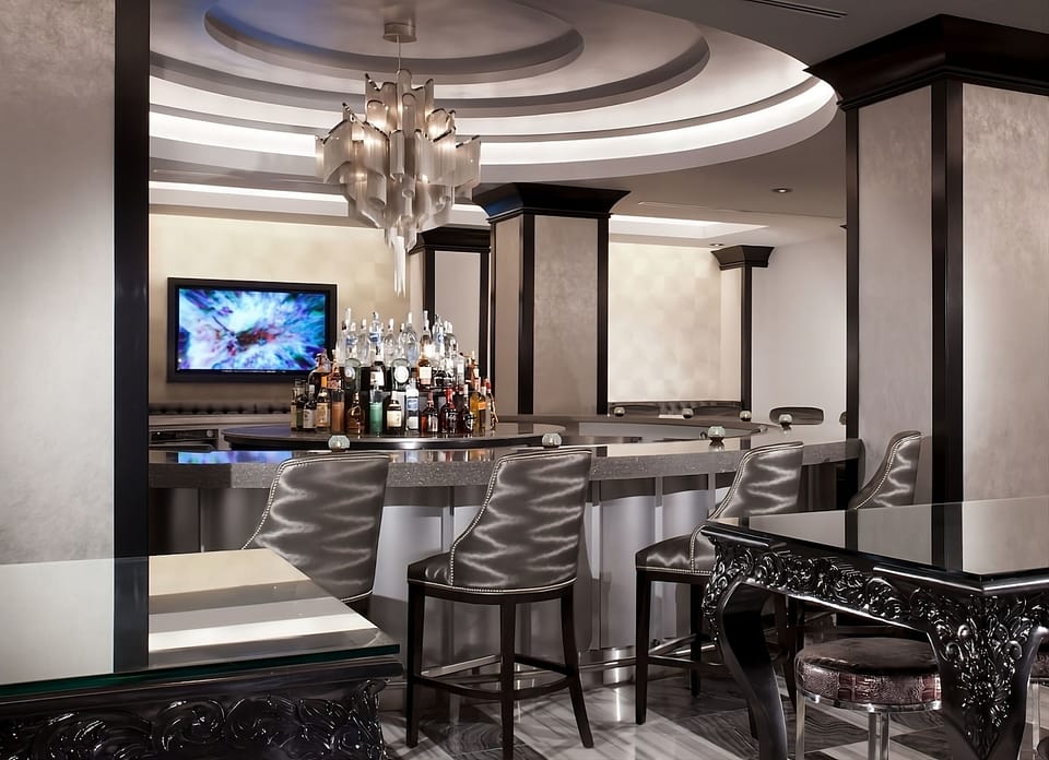 Sip cocktails at a polished bar beneath dramatic lighting.