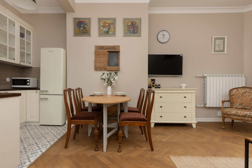A dining area with a wooden table, chairs, and a view of the open kitchen, perfect for meals or work.

