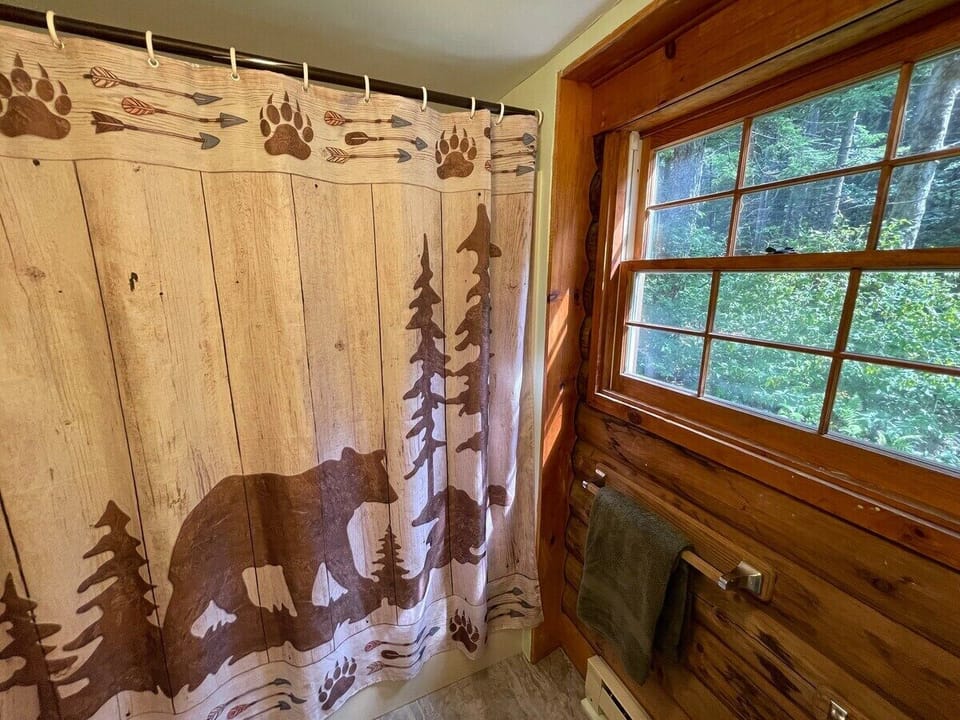 This bathroom is on the first floor of the cabin and has a bath tub and shower head. 