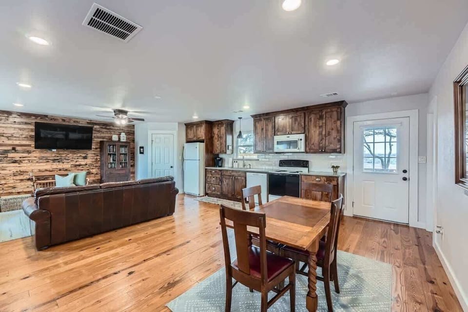 Enjoy an open-concept layout with a fully equipped kitchen, dining area, and living room accented by warm wood finishes.