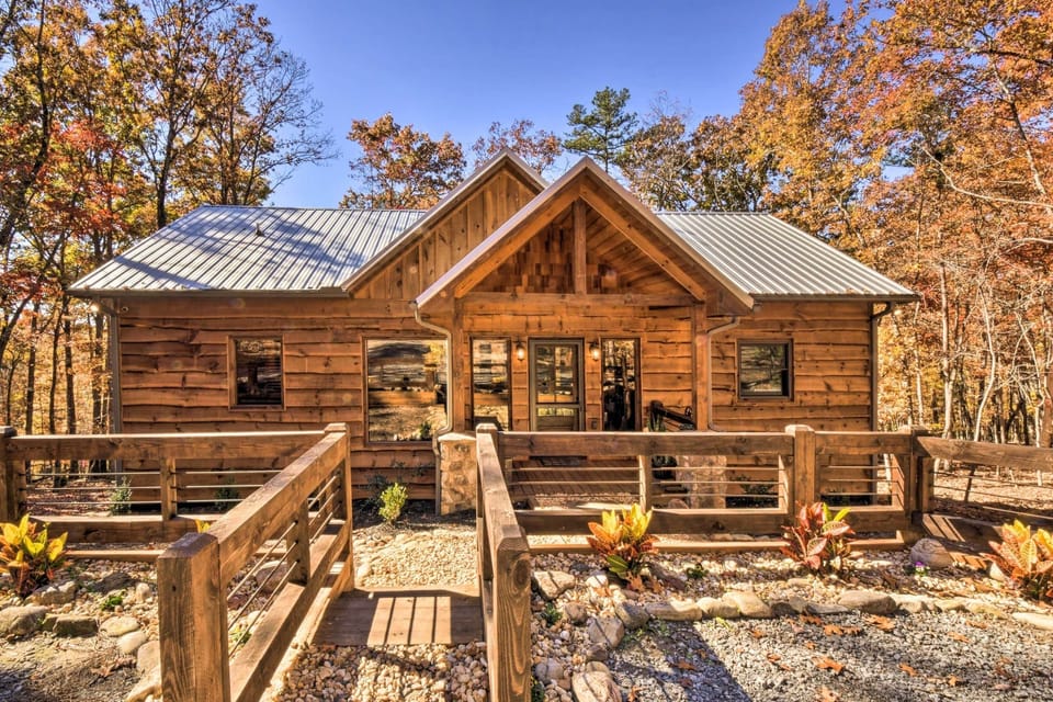 Front view of rustic log cabin with metal roof and wooded entry path in Blue Ridge