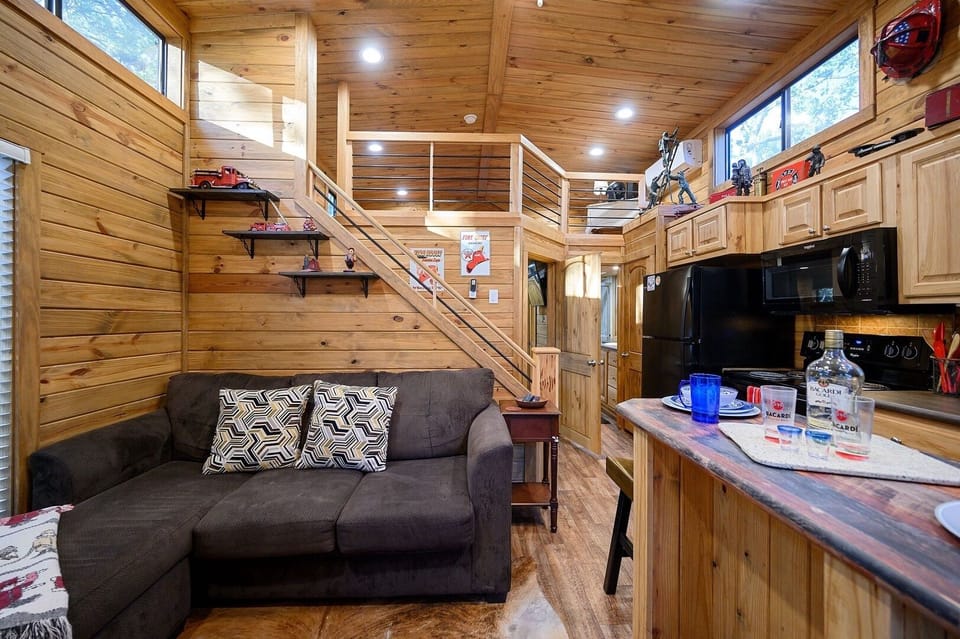 This enchanting tiny home offers an idyllic escape for couples, families, or a small group of friends. Please note: the couch has since been replaced with a new leather love seat and no longer has a lounging seat.