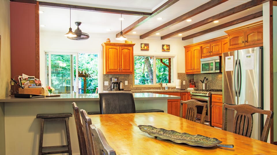 Bar seating for 3 adjacent to dining table in open floor plan kitchen.