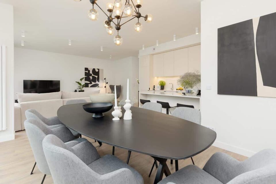 A stylish dining area with soft gray chairs and a round black table set for four.