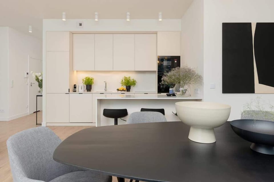 A contemporary kitchen with neutral tones, sleek black island, and modern appliances.