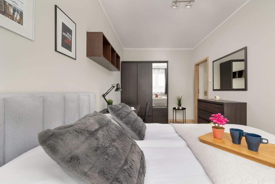 A comfortable bedroom with plush gray bedding and a relaxing, minimalist design.

