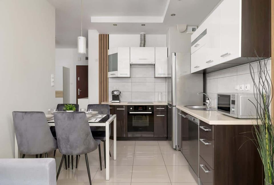A fully equipped kitchen with sleek white and brown cabinetry, complemented by a cozy dining area.

