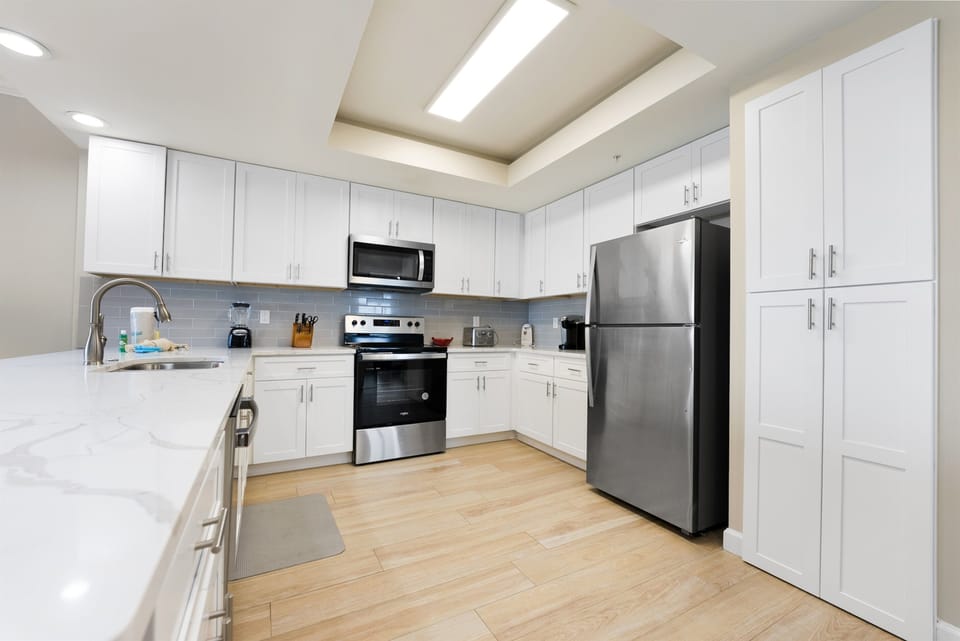 Your spacious kitchen features modern white cabinetry, stainless steel appliances, and everything you need to create memorable meals during your stay.