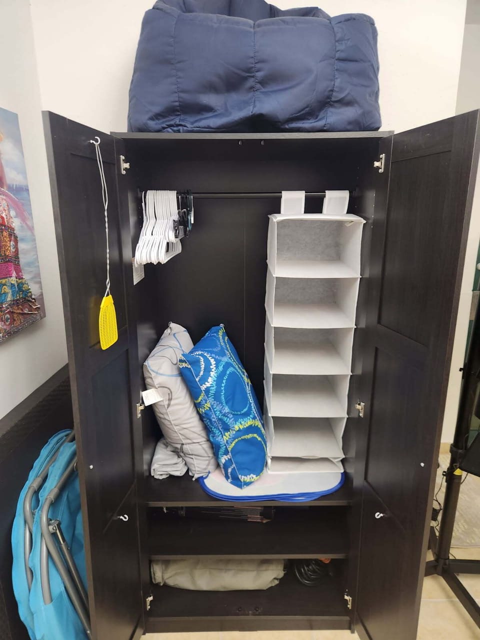 Armoire upstairs: hangars, cubbies, pillows. Chair above. Folding chairs to side