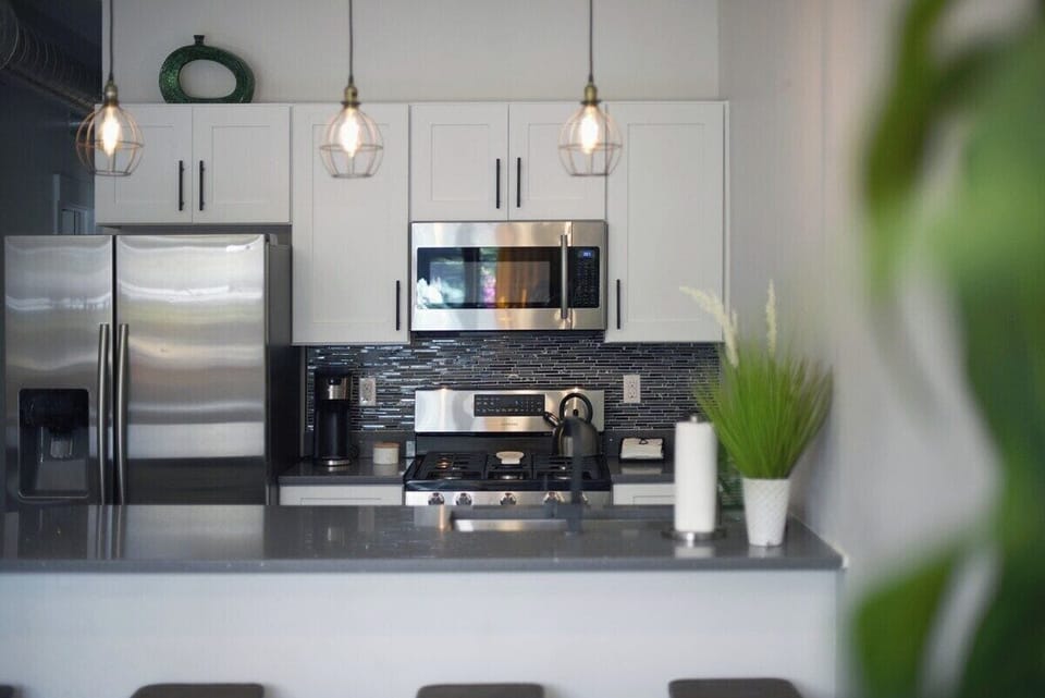 first level fully functioning kitchen includes stainless steel appliances, industrial pendant lighting, coffee supplies, cooking utensils & more
