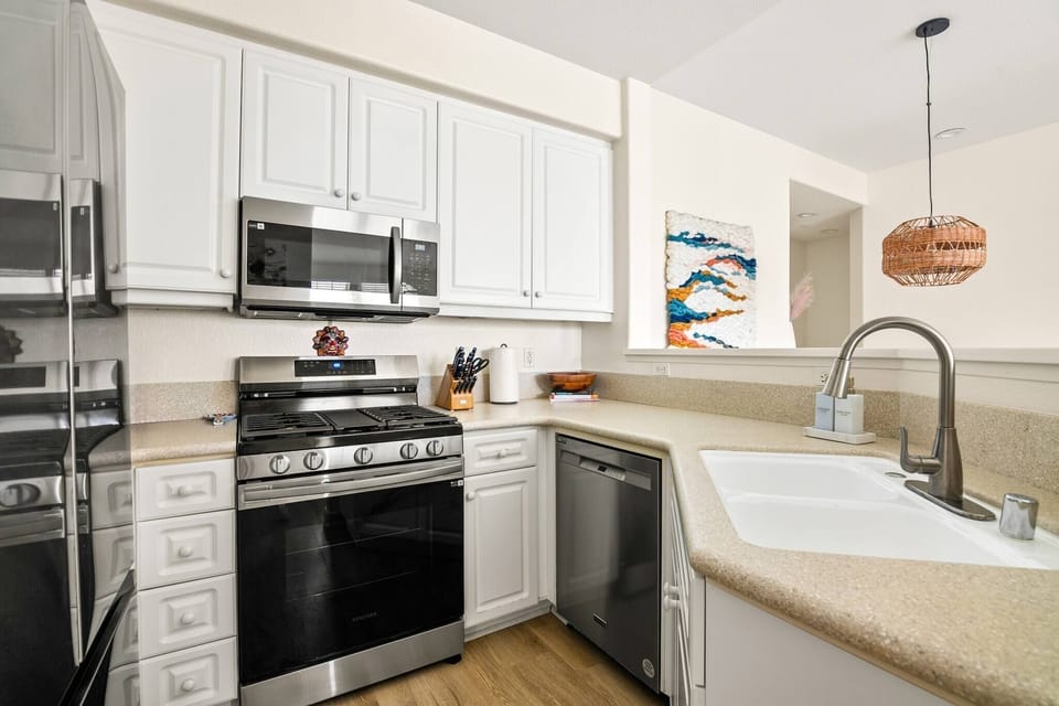 Stainless steel appliances w/white cabinetry and granite countertops