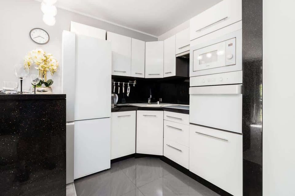 A compact kitchen with white cabinets, black countertops, and built-in appliances for a sleek, functional design.

