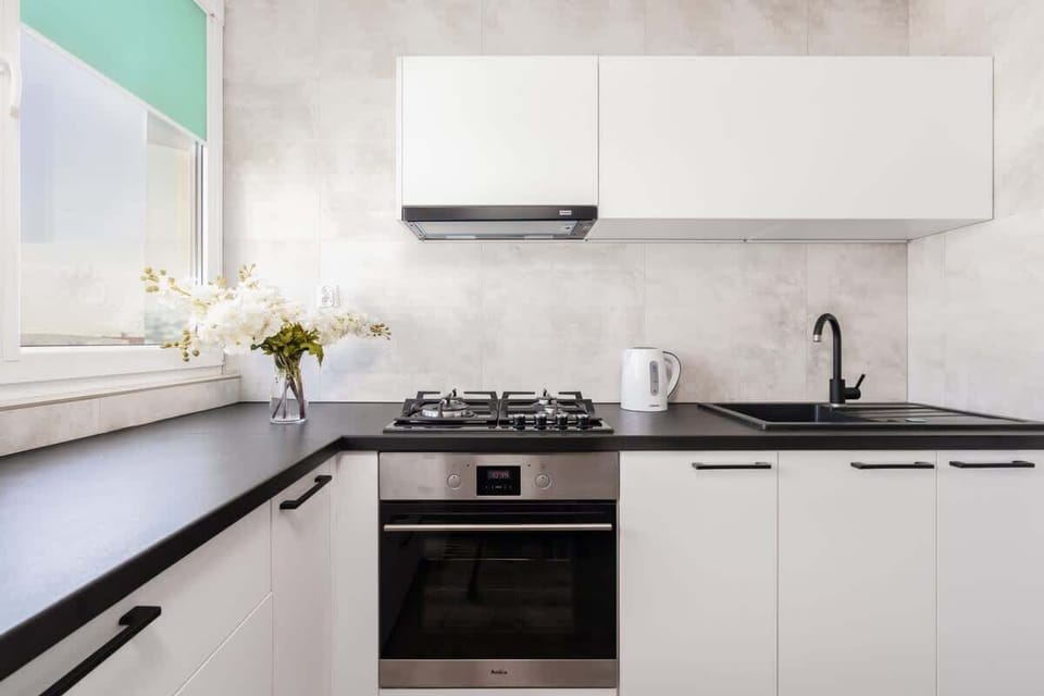 A modern kitchen with white cabinets, a gas stove, and stylish countertops, perfect for preparing meals.

