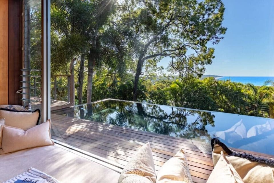 Living room with seating area, infinity pool, and ocean outlook. Bright, modern design ideal for couples or families.
