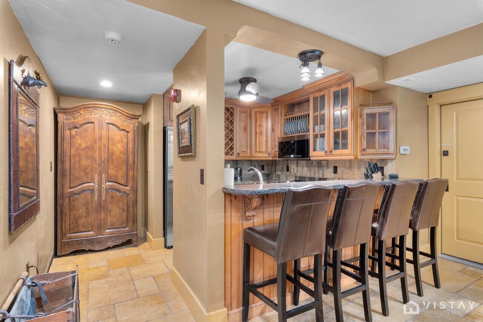 The kitchen features a bar counter with four stools, providing a casual dining area perfect for meals or gathering with friends and family.