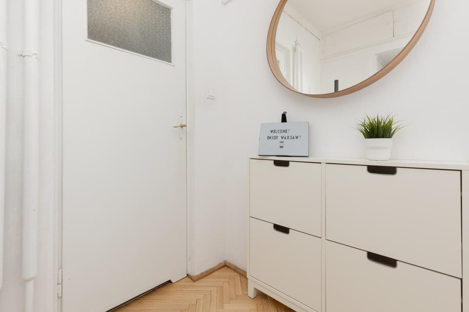 An entryway featuring a minimalist white console, a round mirror, and small decorative accents.

