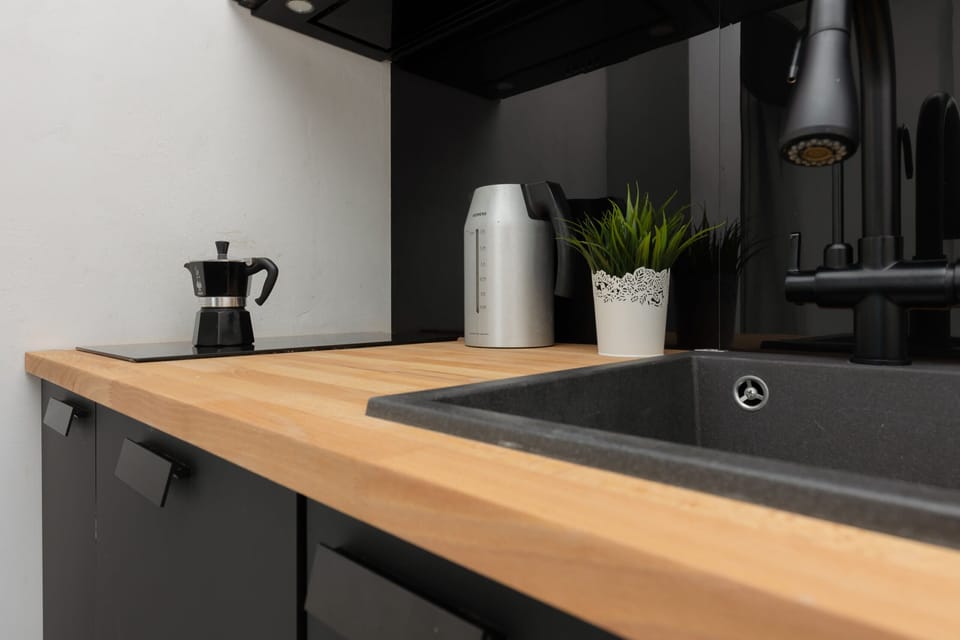 A kitchen close-up showing the sleek black sink, wooden countertop, and simple decor for a clean design.

