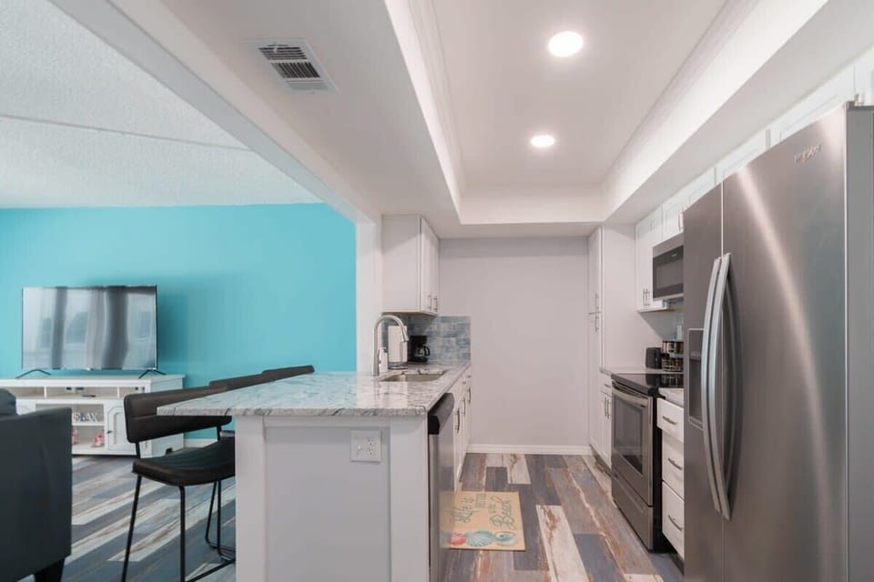 Modern kitchen with stainless steel appliances and a breakfast bar overlooking the living area.