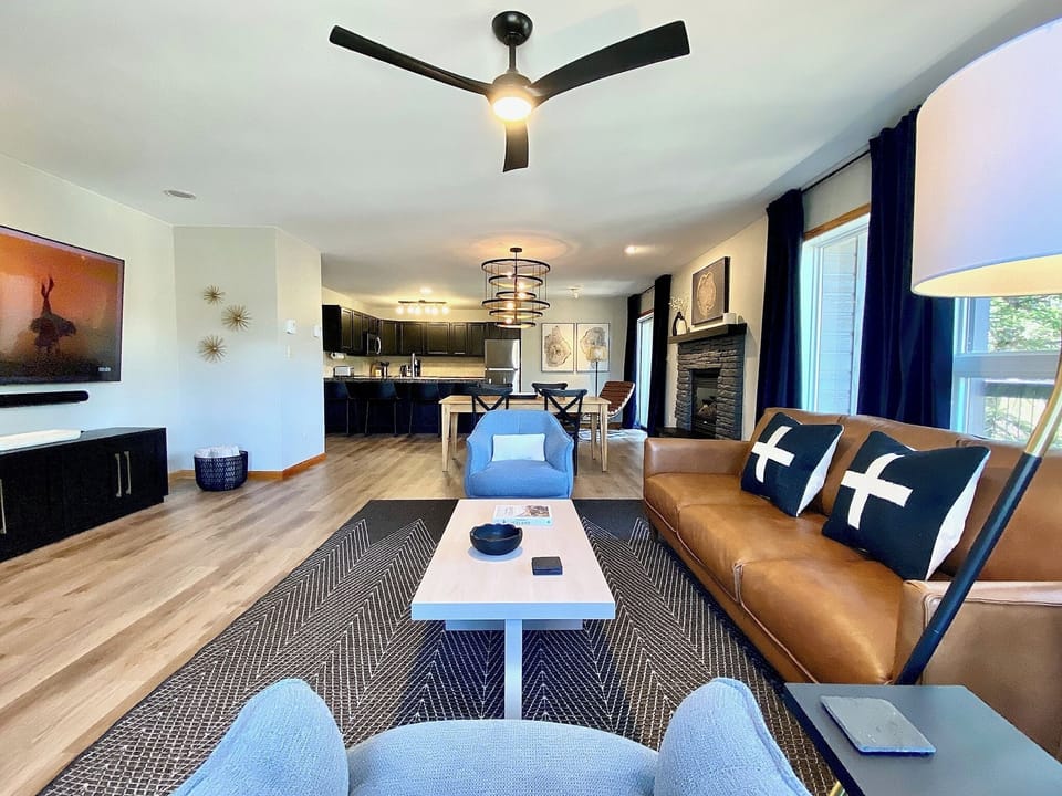 Living room with seating for five and a 75" smart TV and Sonos speaker. 