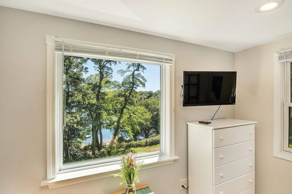 Queen bedroom facing Crystal Lake across large lawn. Roku-equipped TV.