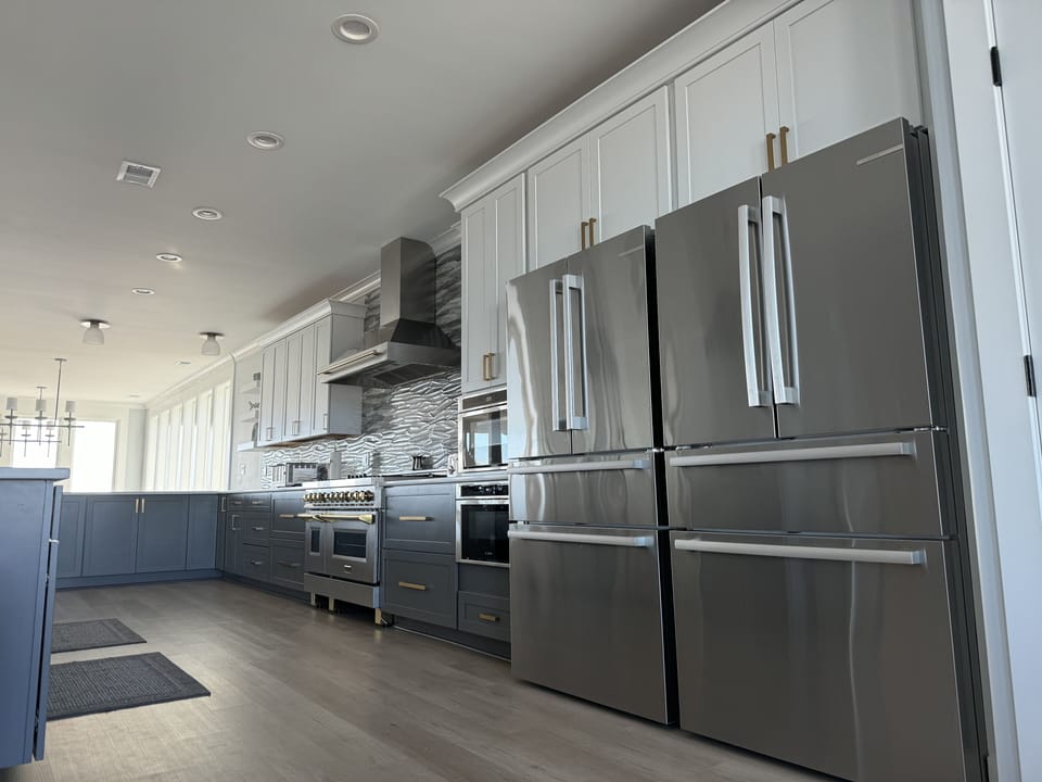 Kitchen with two refrigerators and two microwaves. 


