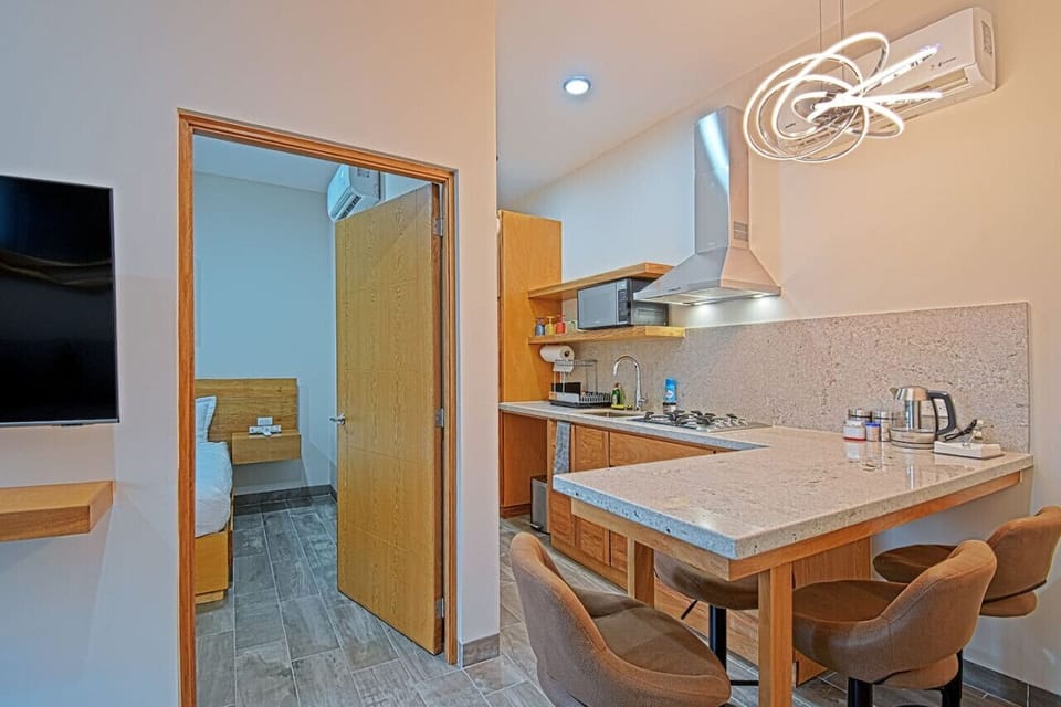 Disfruta de una cocina sofisticada con cubierta de granito blanco, equipada con microondas, parrilla, campana y vajilla. La barra desayunador para 4 personas te invita a relajarte en un entorno moderno y elegante. ¡Todo listo para tu comodidad!