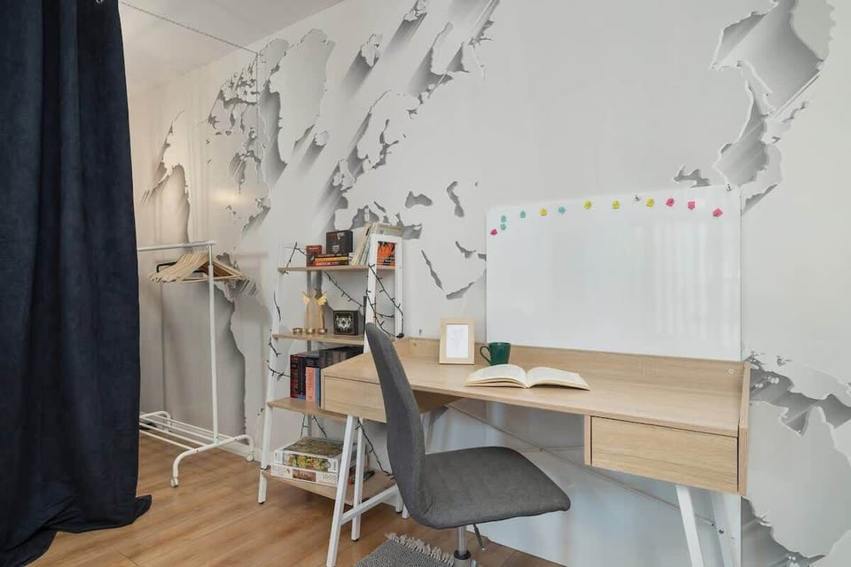 A workspace with a wooden desk, chair, and wall-mounted world map, ideal for productivity and creativity.

