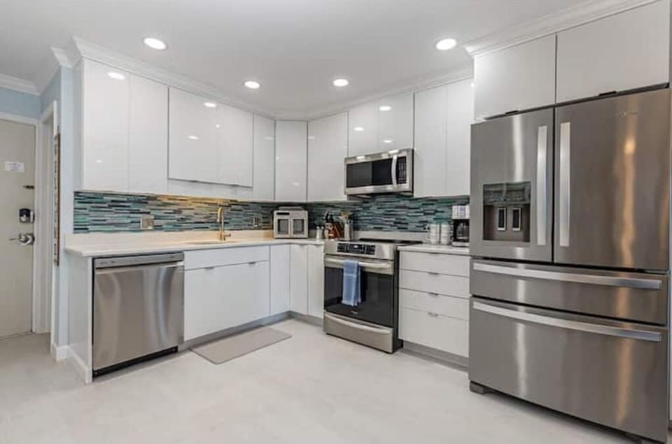 Modern kitchen with stainless steel appliances and back splash.