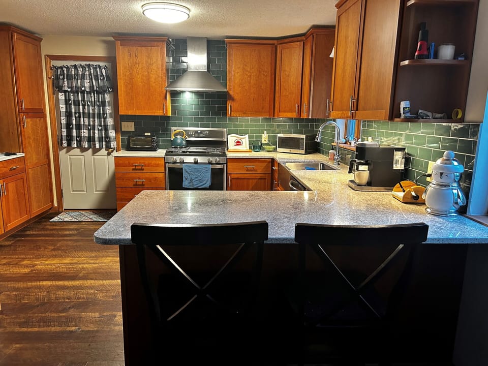 New kitchen with cherry cabinets, dishwasher, quartz countertops, and TV.