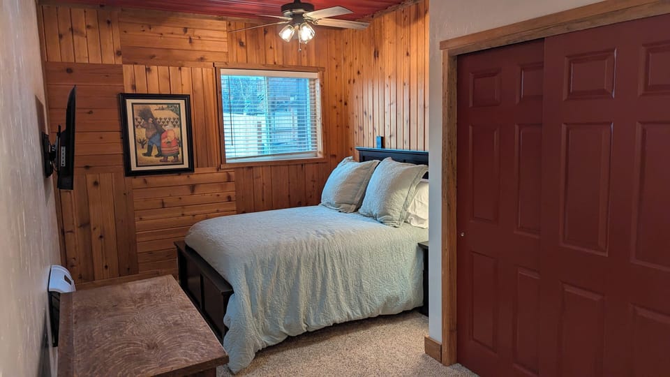 Bedroom with queen bed and wall-mounted TV
