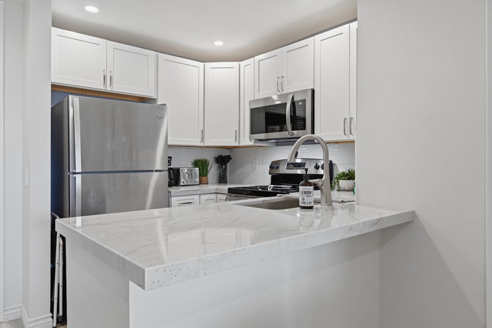 Fully stocked kitchen ready for beach snacks or full family meals, equipped with a dishwasher, microwave, toaster, and all essential cookware.