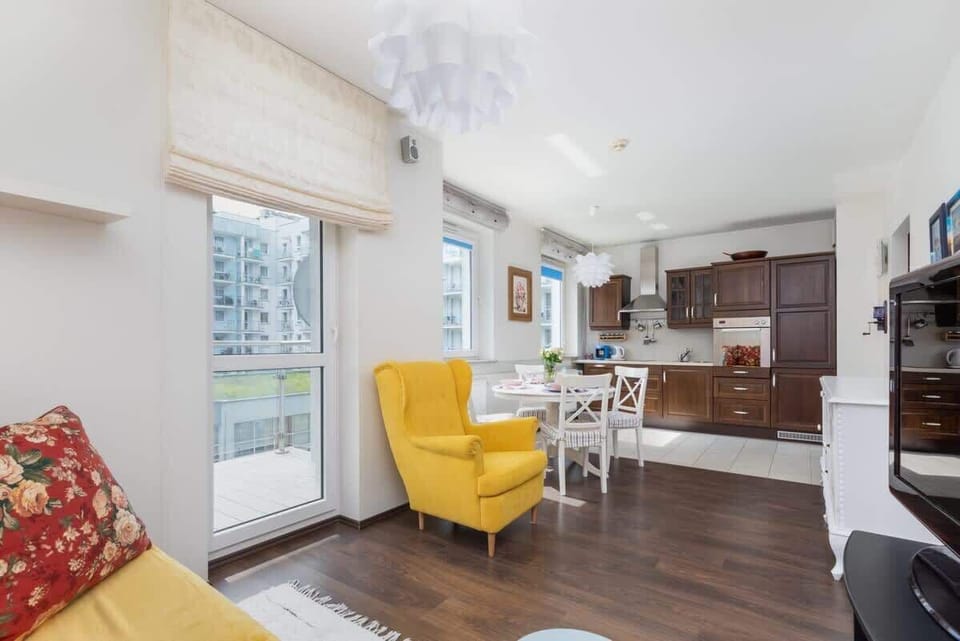 Another view of the living room, highlighting the floral sofa and yellow armchair in natural light.
