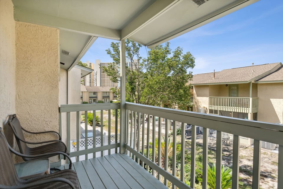 Relax on the covered balcony with views of the surrounding neighborhood and greenery.