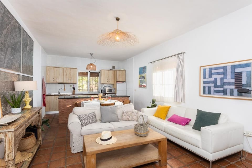 Open-plan living room with sofas, dining area, kitchen, ornamental fireplace, A/C, WiFi internet, and satellite TV