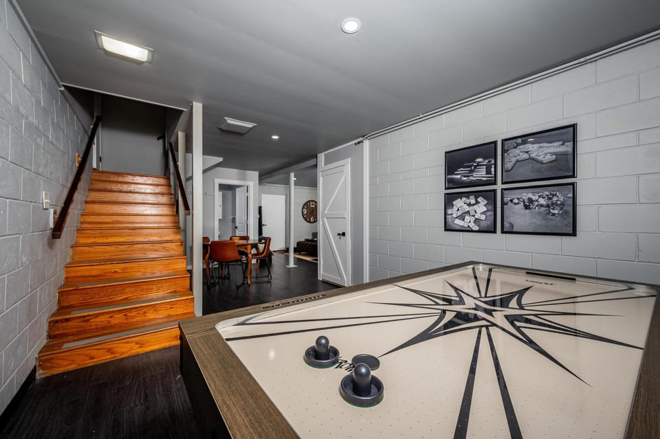 Bathroom showcases black fixtures atop a warm wood vanity with white tiled walls and a round mirror.