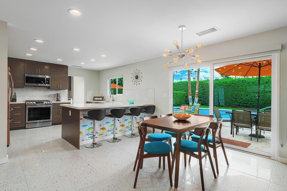 Dining table for 6 and bar seating for 4. Glass doors open to backyard pool area