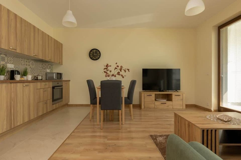 A fully equipped kitchen with light wooden cabinets and a modern backsplash.
