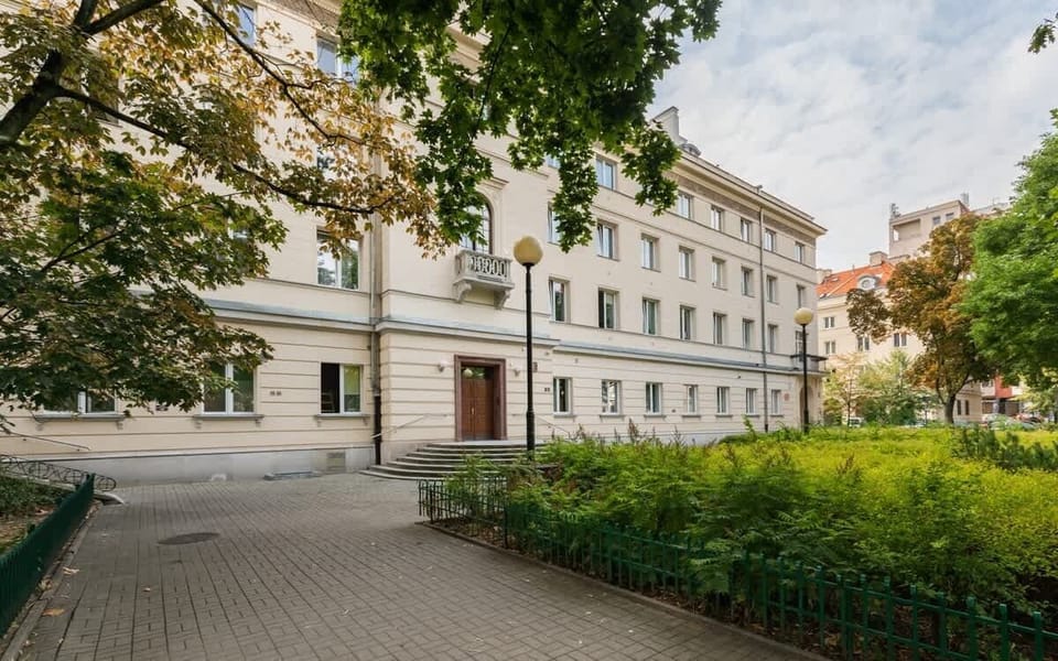 An exterior view of the building surrounded by greenery, emphasizing the quiet and charming location.

