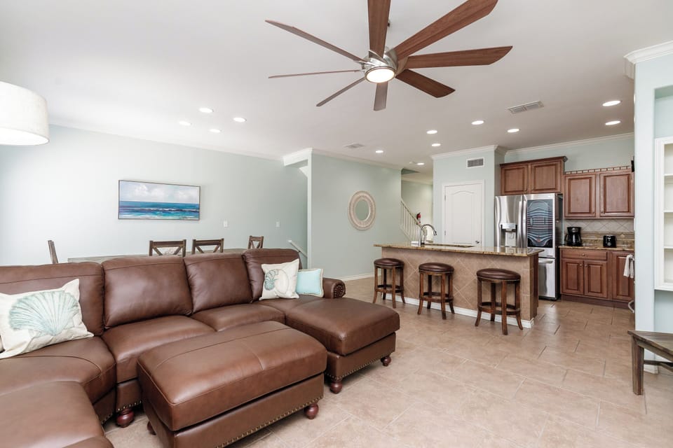 Relax in your spacious living area with plush leather seating and open kitchen featuring breakfast bar—perfect for unwinding after beach days.