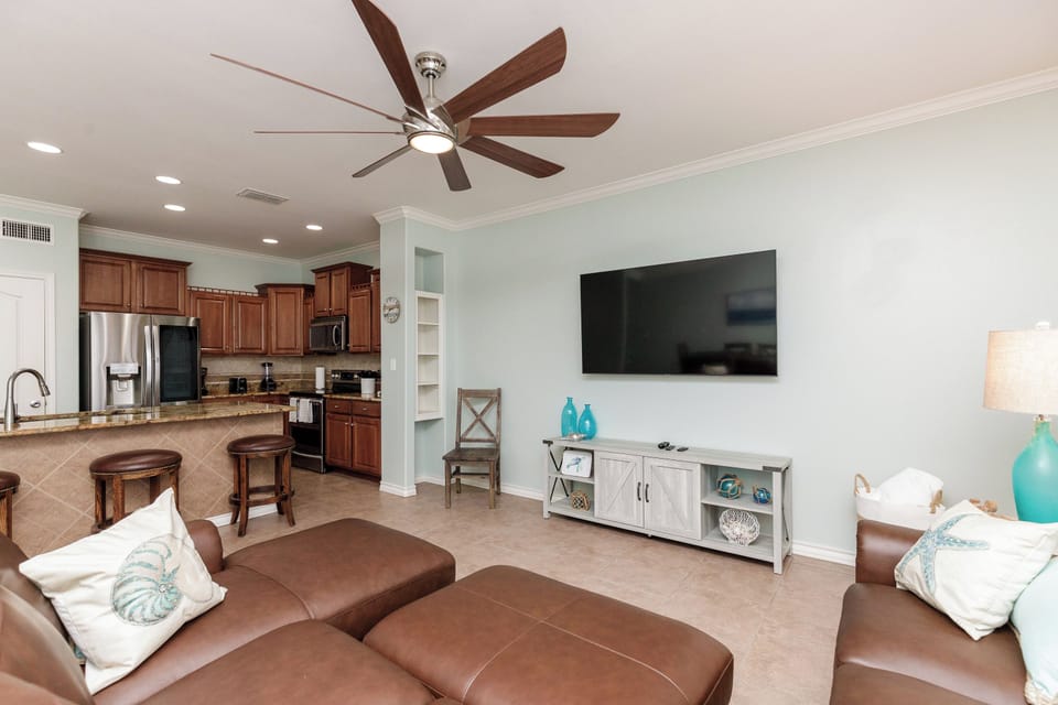 Unwind in your spacious open-concept living area where rich wood cabinets and leather seating create the perfect coastal retreat atmosphere.