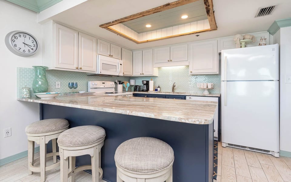 Bright kitchen area featuring a stylish breakfast bar with cushioned stools, elegant backsplash, and ample cabinetry