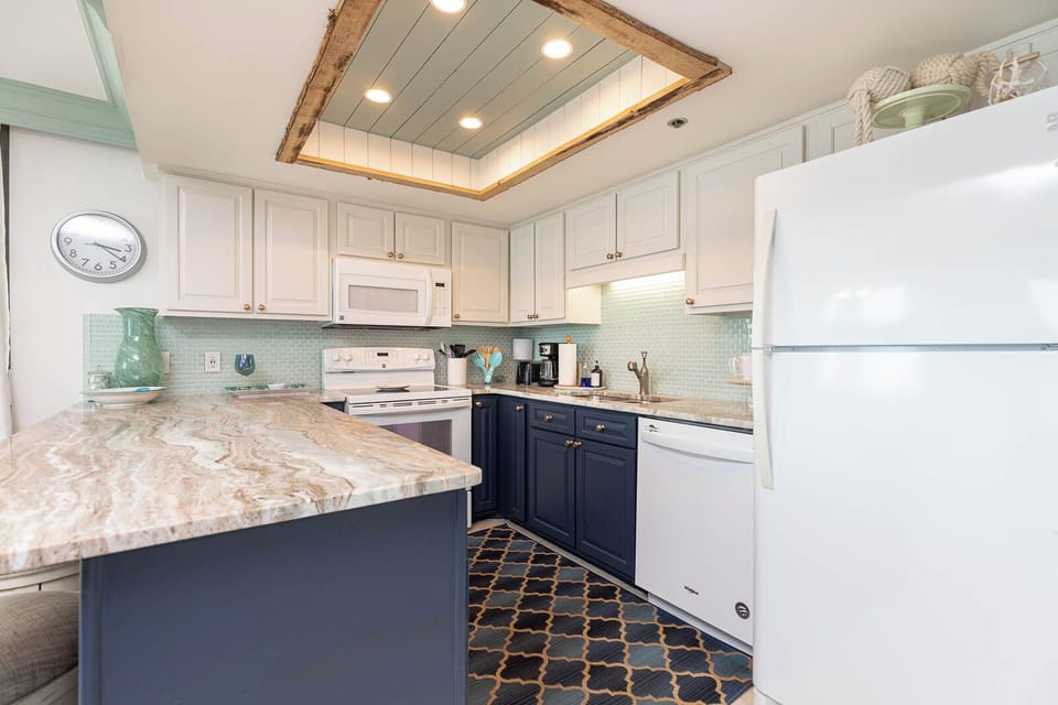 The modern kitchen features elegant blue cabinetry, a spacious countertop, and a decorative ceiling with recessed lighting