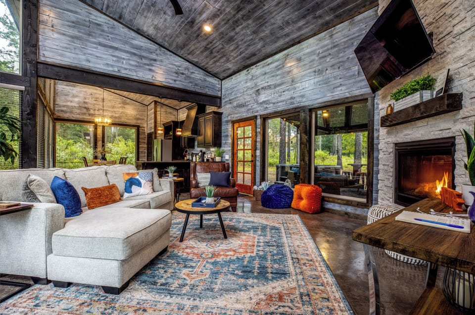 Picture of the living room with the kitchen in the background and also the windows and doorway out onto the back porch.
