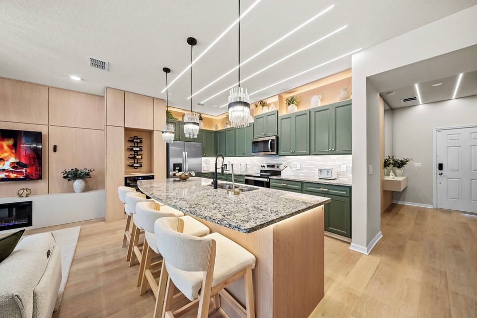 Experience a beautiful kitchen with rich green cabinetry and elegant granite countertops that inspire culinary creativity, while stylish bar seating and modern lighting set a vibrant atmosphere for meals and sharing stories.