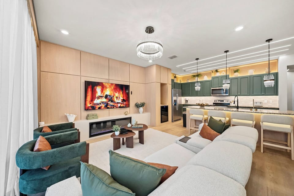 Unwind in this chic living area with a comfy sectional and colorful accent chairs, ideal for cozy evenings. The inviting fireplace and modern kitchen cabinetry set a warm atmosphere for memorable gatherings.