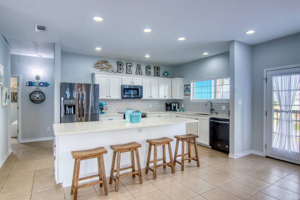 Kitchen island offers seating for four and ample workspace for preparing meals in the fully stocked kitchen.