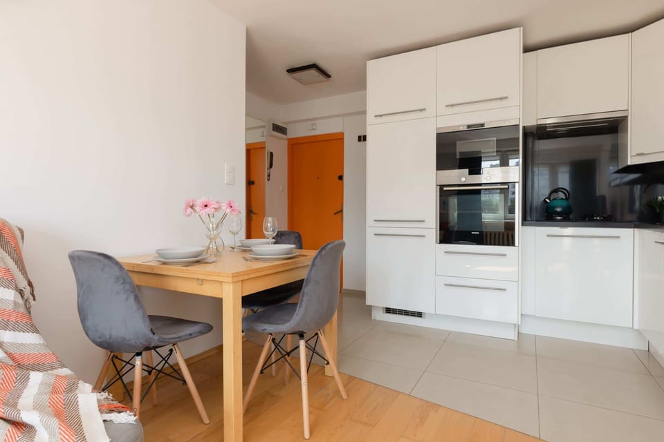 A dining area with a round wooden table and modern chairs, conveniently located near the kitchen.

