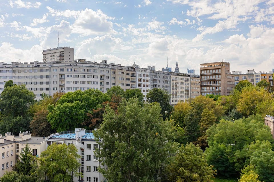 A scenic view of the surrounding neighborhood, with lush greenery and residential buildings in the distance.
