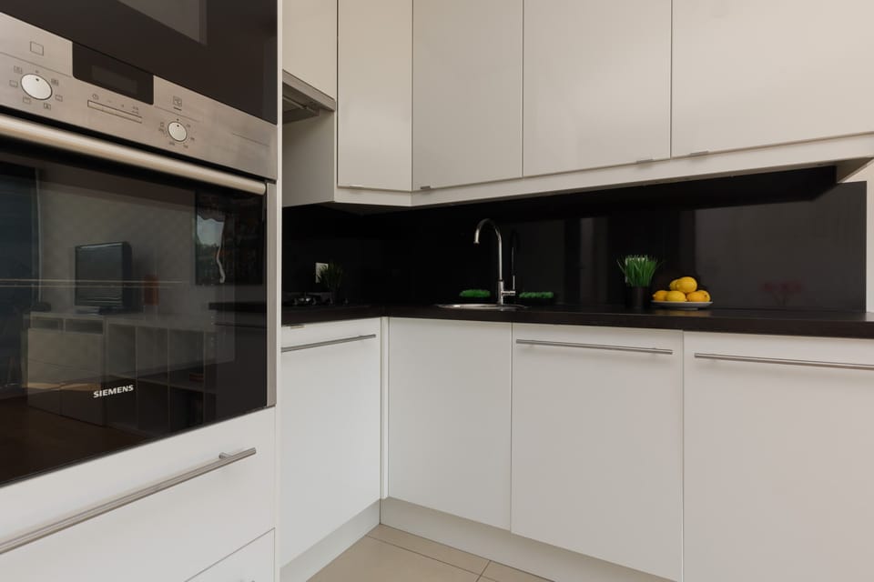 A sleek kitchen with white cabinetry, black countertops, and built-in appliances for a functional and stylish space.

