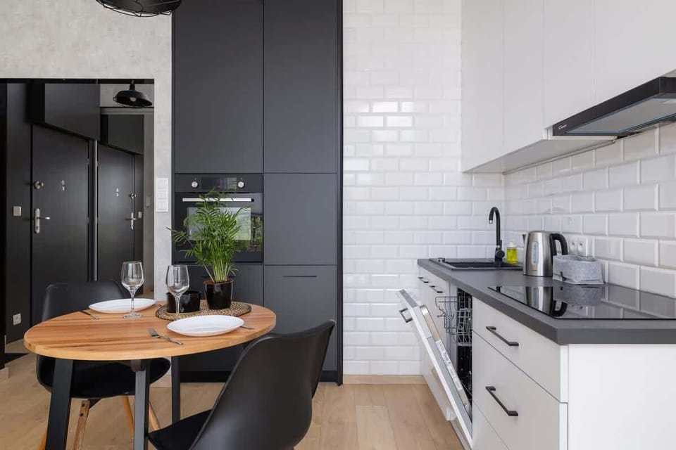 A modern kitchen with sleek cabinets, a round dining table, and a fresh plant adding a vibrant touch.

